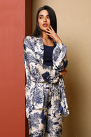 Woman wearing a floral kimono-style outfit against a beige wall.