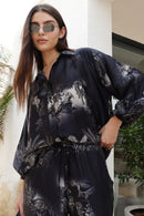 Woman wearing a black patterned outfit standing outdoors.