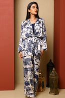 Woman wearing a blue and white floral outfit against a beige and red wall.