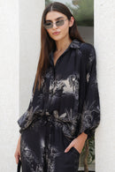 Woman wearing a black floral outfit against a white wall