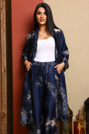 Woman wearing a long navy blue floral dress against a beige wall.