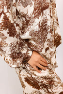 Close-up of a hand holding a patterned fabric with brown and beige design on a white background