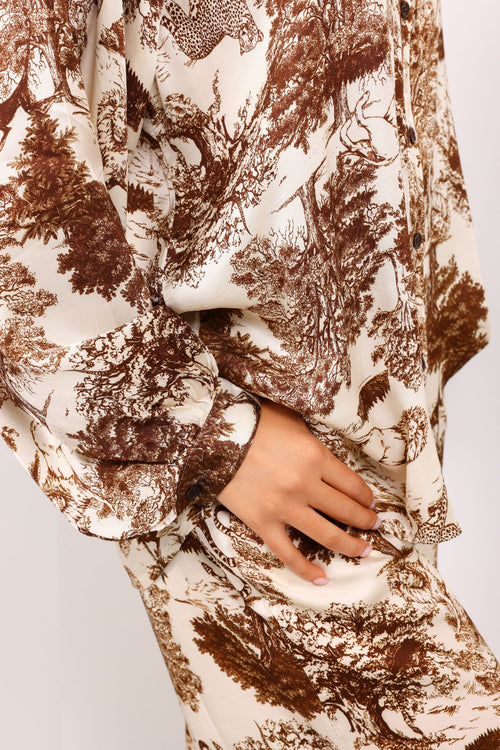 Close-up of a hand holding a patterned fabric with brown and beige design on a white background