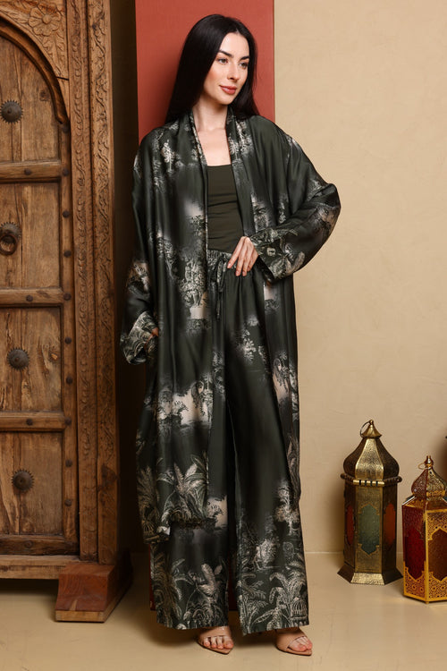 Woman wearing a black floral kimono-style outfit standing in a room with wooden furniture and lanterns.