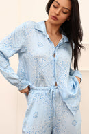 Woman wearing a light blue patterned outfit against a neutral background