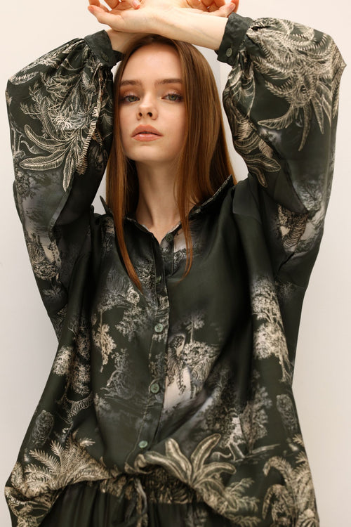 Woman wearing a dark floral patterned outfit with a plain background