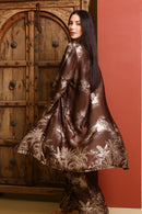 Woman wearing a brown floral dress in front of a wooden door.