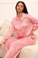 Woman wearing a pink paisley outfit sitting on a beige couch.