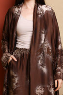 Brown floral-patterned robe over a white top and skirt against a red background