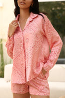 Woman wearing a pink patterned outfit with a blurred outdoor background