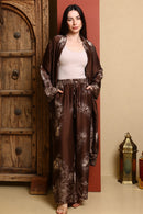 Woman wearing a brown floral outfit standing in front of a wooden door.