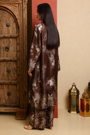 Woman in a patterned outfit standing in a room with wooden furniture and lanterns.