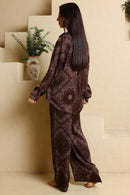 Woman in a patterned outfit standing on a staircase with a plant in the background