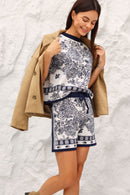 Woman wearing a Navy outfit with beige jacket against a textured white background