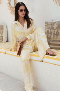Woman in a yellow patterned outfit sitting on a couch with decorative pillows.