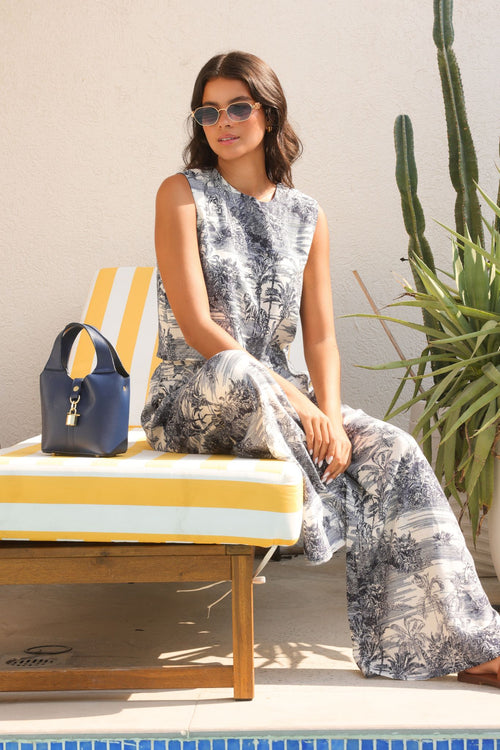 Woman sitting on a sun lounger by a poolside with a cactus plant in the background