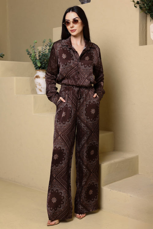 Woman wearing a patterned outfit standing on a staircase with a neutral background