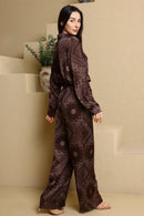 Woman wearing a brown patterned outfit standing in a minimalistic room.