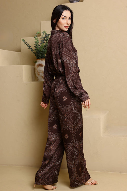 Woman wearing a brown patterned outfit standing in a minimalistic room.