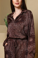 Woman wearing a brown patterned outfit against a beige background