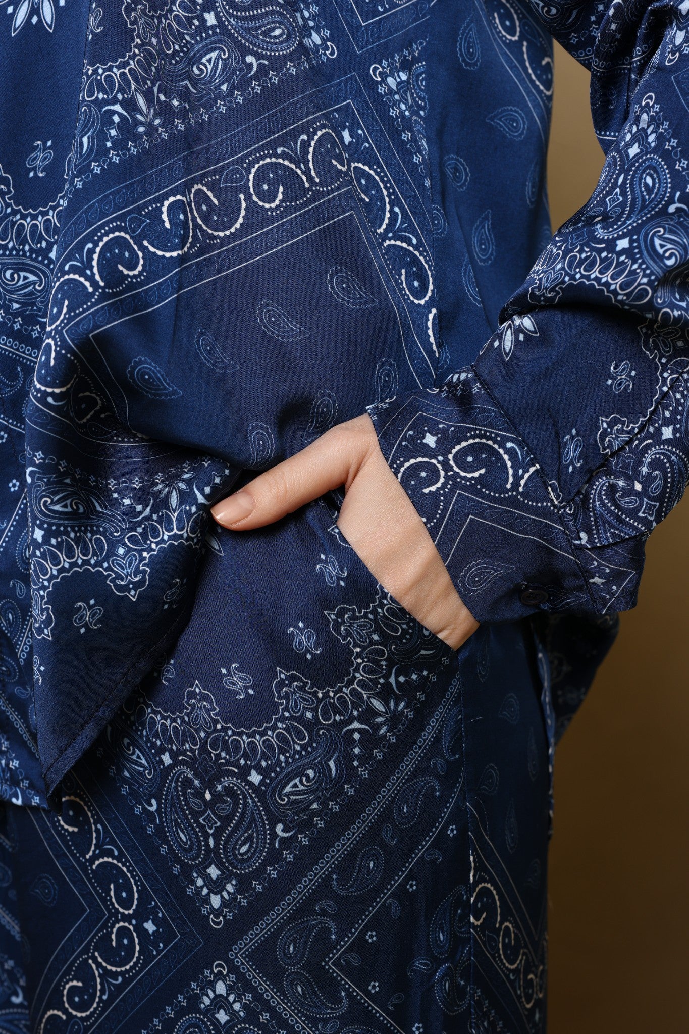Navy blue fabric with white paisley pattern, held by a hand against a brown background