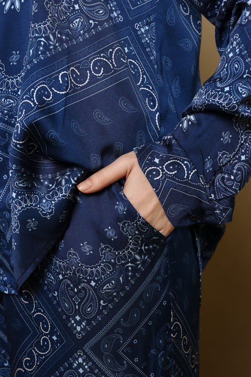 Navy blue fabric with white paisley pattern, held by a hand against a brown background