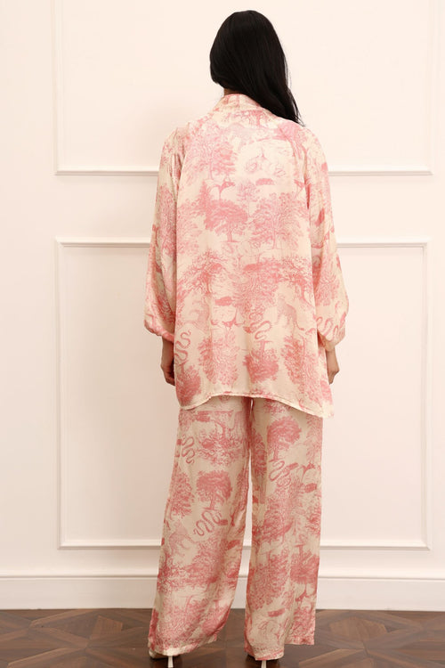 Person wearing a pink kimono outfit standing against a white paneled wall.
