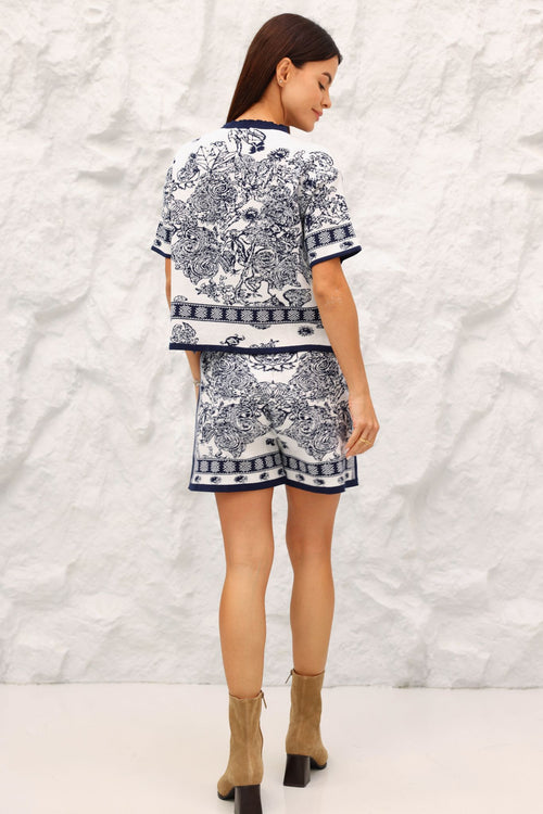 Woman wearing a Navy and white patterned outfit against a textured white background