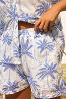Close-up of a person wearing a white outfit with blue palm tree pattern.