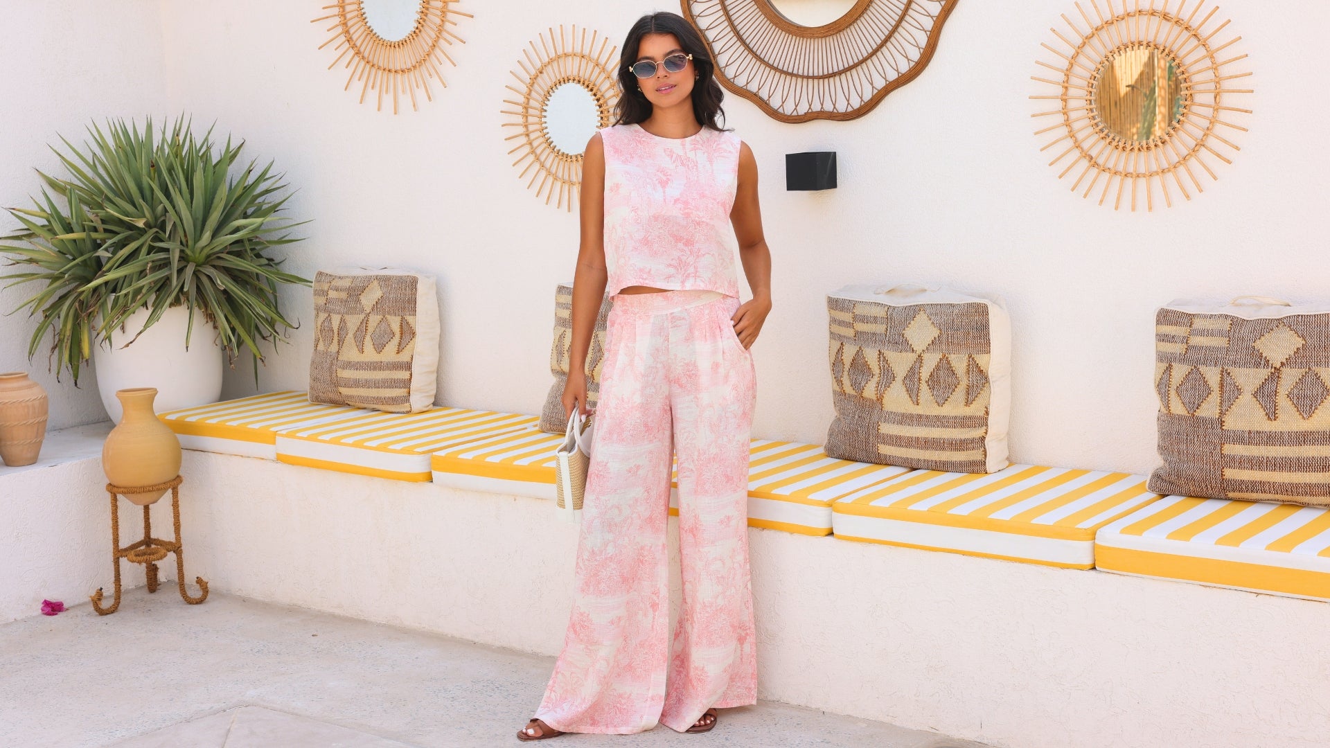 Woman in a pink outfit standing in a stylish interior setting with decorative elements.