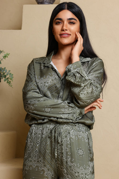 Woman wearing a green patterned outfit against a beige background