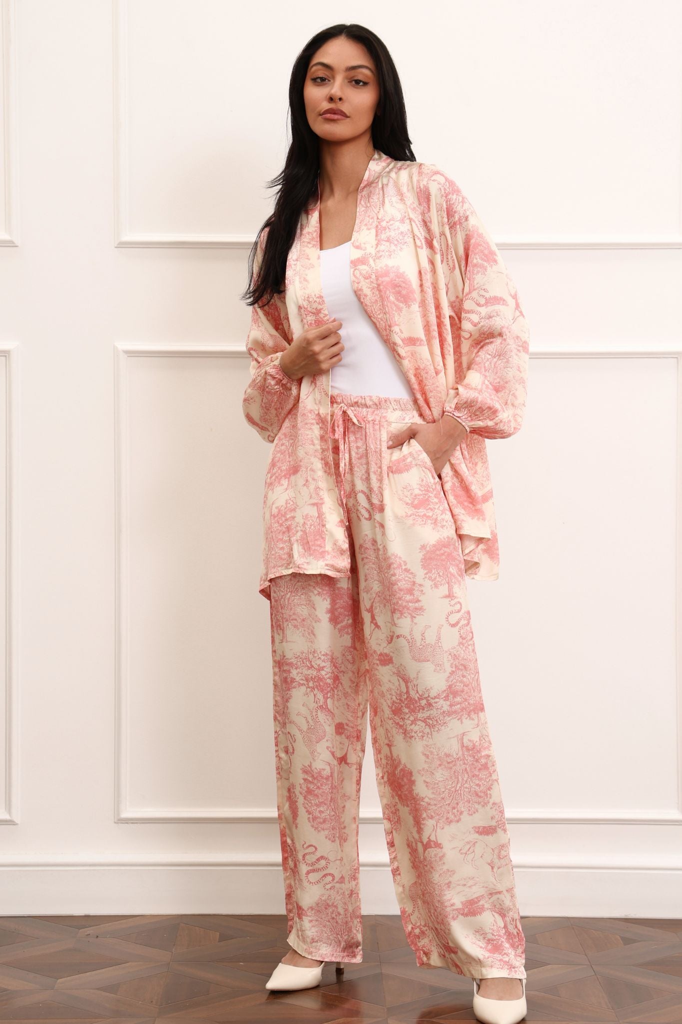 Woman wearing a pink kimono set against a white wall.