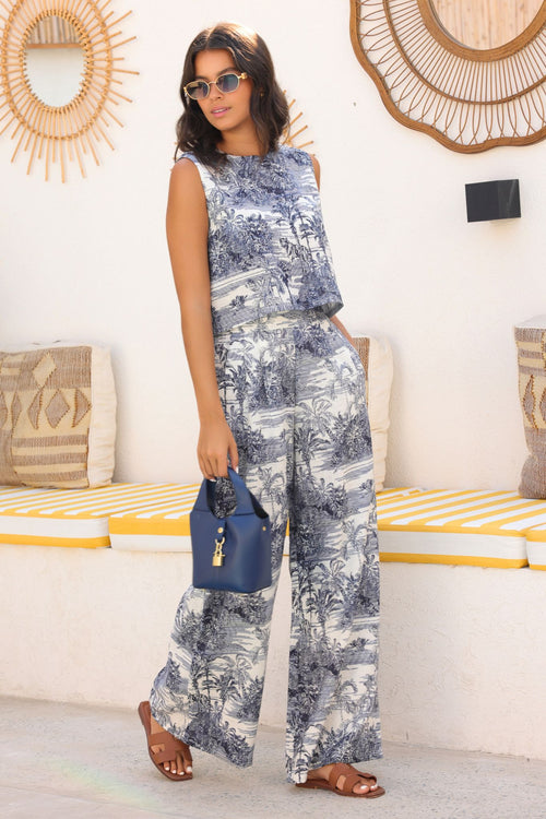 Woman in a floral outfit standing in a room with decorative mirrors and a couch.