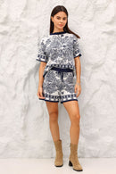 Woman wearing a navy outfit against a textured white wall