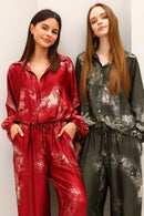 Two women wearing floral-patterned jumpsuits against a plain background