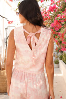 Woman wearing a pink floral dress with a blurred background of flowers