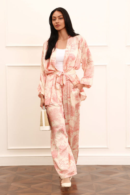 Woman wearing a pink kimono set against a white background and wooden floors