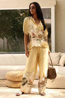 Woman in a yellow outfit with a scenic print standing in a living room.