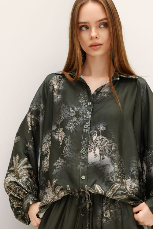 Woman wearing a dark green floral patterned blouse against a white background