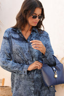 Woman in a blue patterned shirt holding a blue handbag.