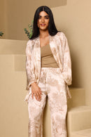 Woman wearing a beige and white patterned outfit standing on a staircase.