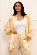 Woman wearing a yellow and white outfit with a matching cardigan against a plain background