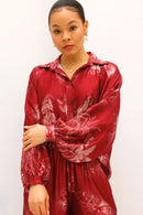 Woman wearing a red patterned outfit against a white background